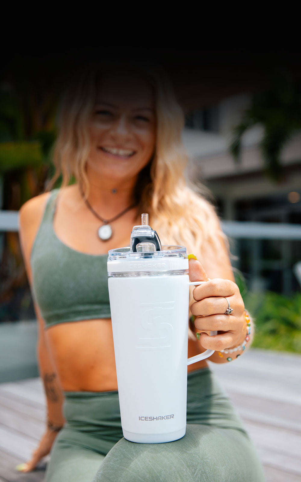 A young, athletic lady holding a white Ice Shaker Flex Bottle with Handle