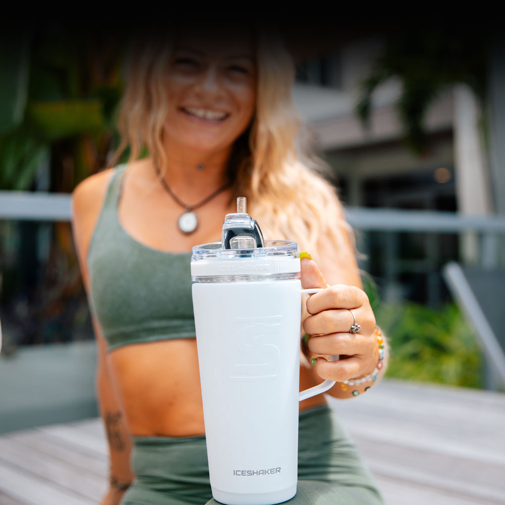 A young, athletic lady holding a white Ice Shaker Flex Bottle with Handle