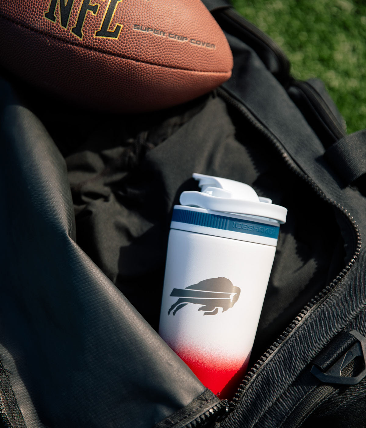 A USA-colored Buffalo Bills engraved Ice Shaker sitting inside a workout bag with a football laying next to it.