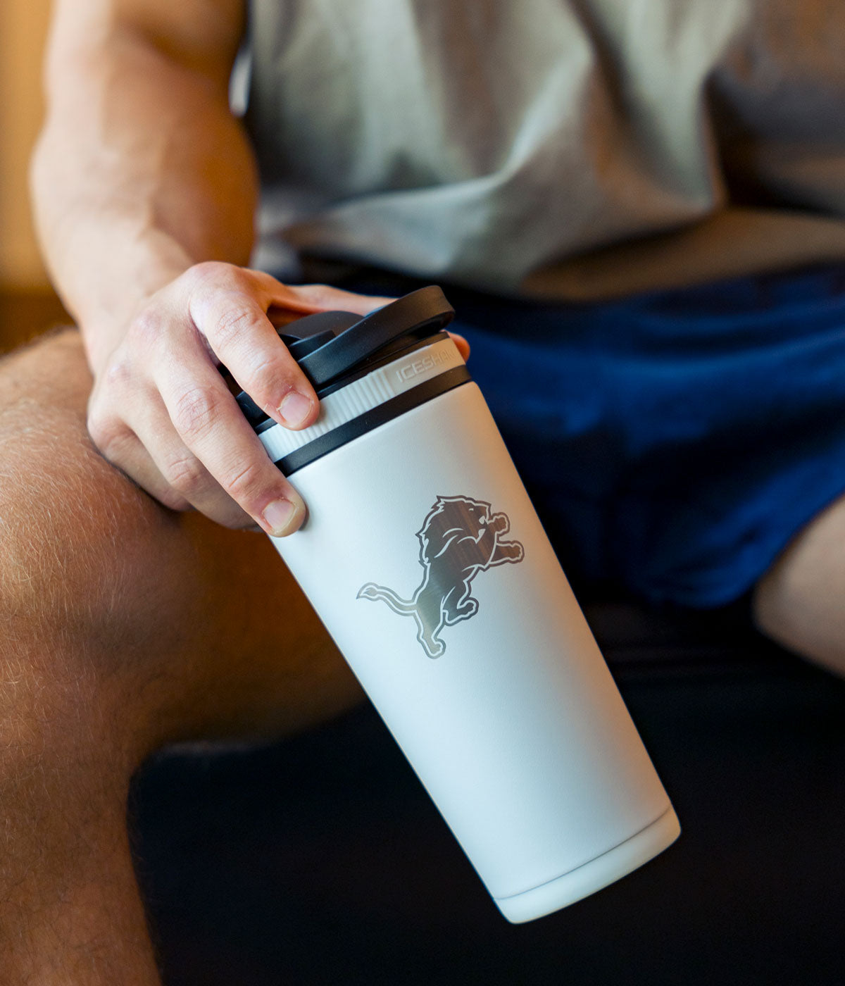 a man holding a white Detroit Lions engraved Ice Shaker.